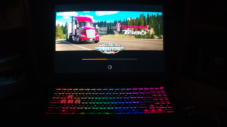 MSI Crosshair 16 sitting open on a desk in the dark with "American Truck Simulator" on the screen