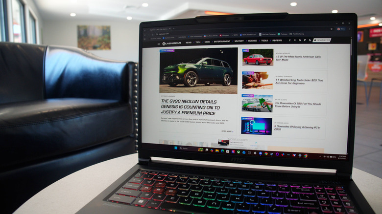 MSI Crosshair 16 sitting open on a table with the SlashGear front page on the screen