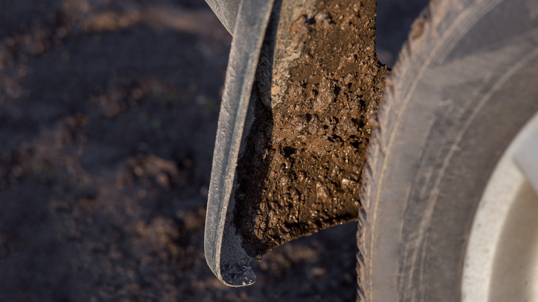 Flaps covered in mud under car next to tire