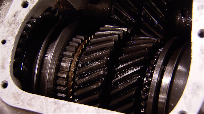 Oil-coated helical gears inside an open Muncie M20 gearbox case
