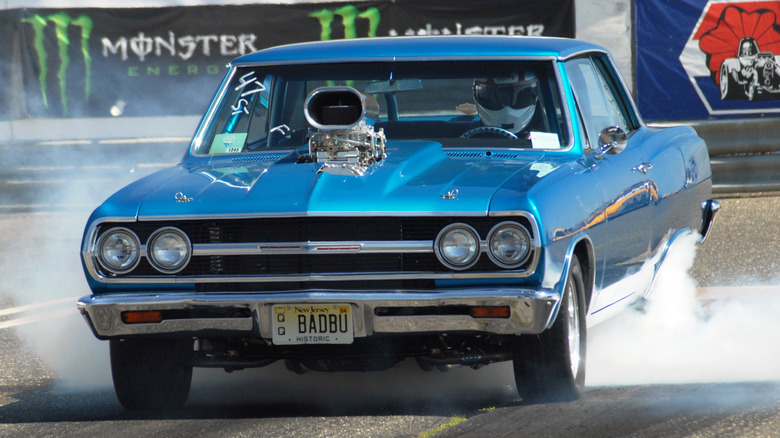 Modified 1965 Chevrolet Chevelle with Roots supercharger and open air scoop performing burnout during drag race staging