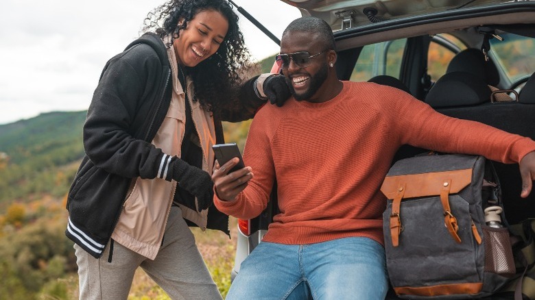 Two people on phone with car trunk open