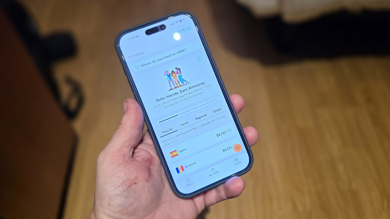 Man holding an iPhone with the Airalo App open