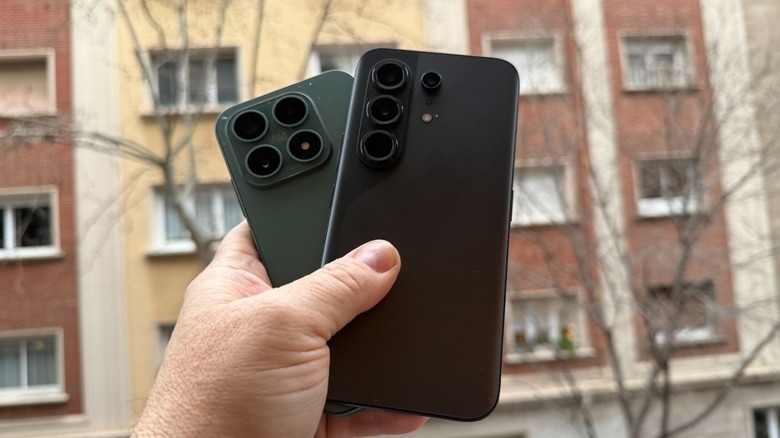 Hand holding up Tecno Camon 50 Pro and Xiaomi 17 smartphones outdoors