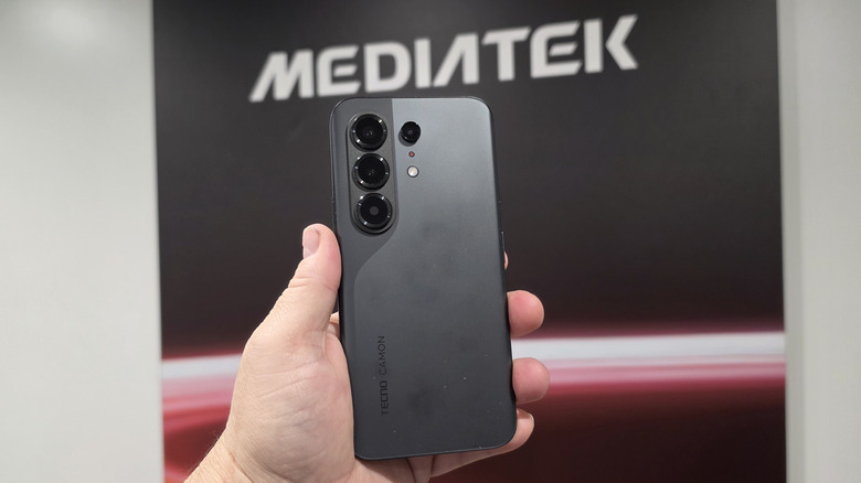 Hand holding a Tecno Camon 50 in front of a MediaTek banner