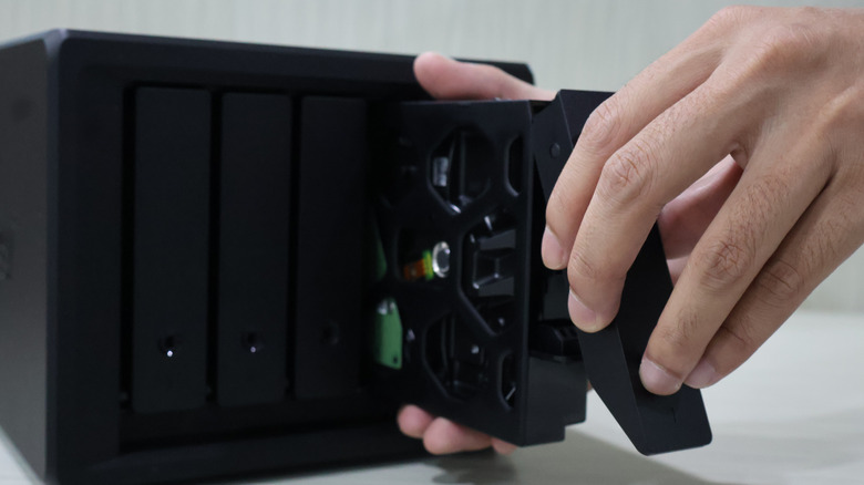 Close up of someone's hand inserting a storage bag into a NAS unit