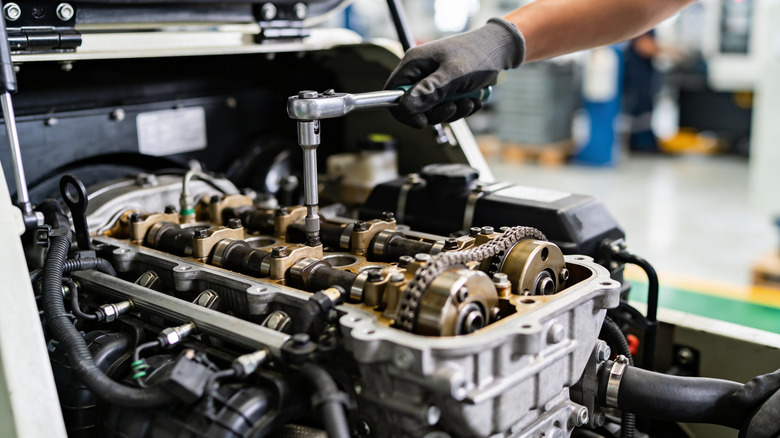 Close up view of mechanic working on  four-cylinder engine.