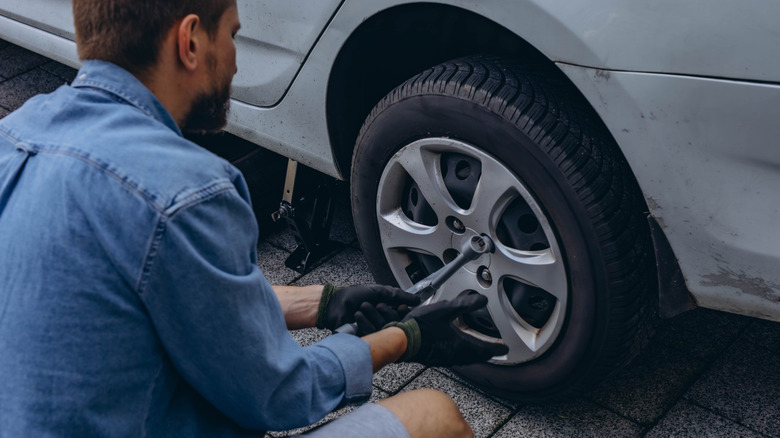 A person changing a tire on a car.