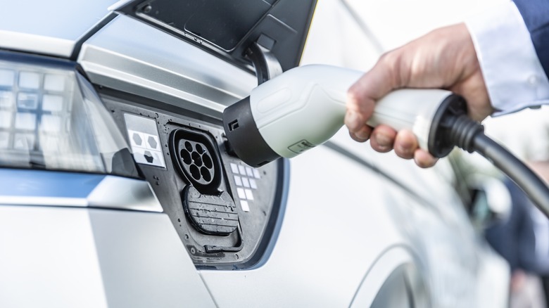 man plugging in electric vehicle charger