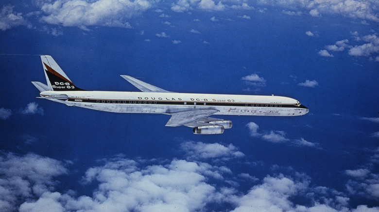 A Douglas DC-8 Super 63 mid-flight with clouds surrounding it, side view