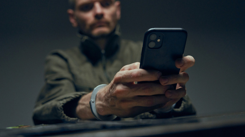 Person in handcuffs using iPhone