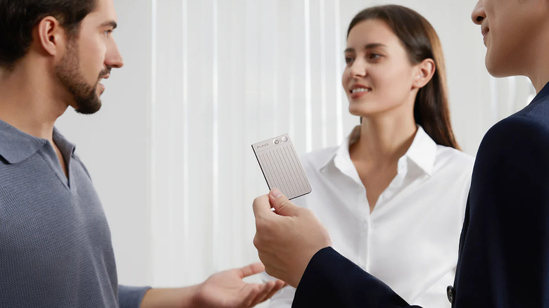 Man holding a PLAUD NOTE in a meeting