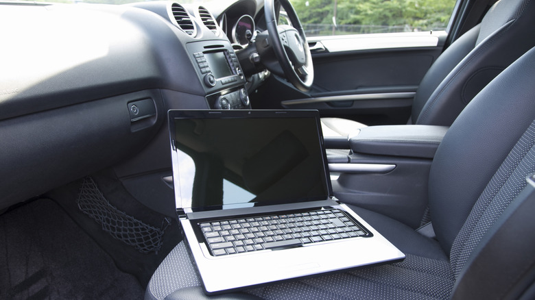 Laptop laying on passenger seat in vehicle interior