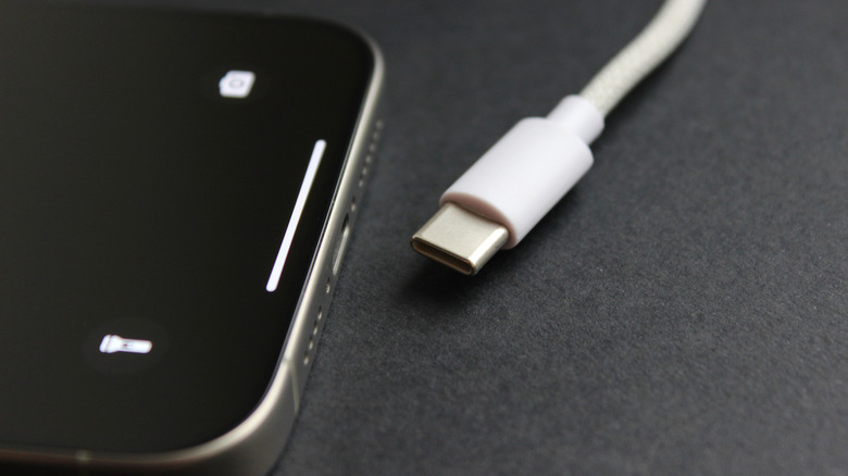 Close-up of a USB-C cable next to a modern smartphone on a dark surface