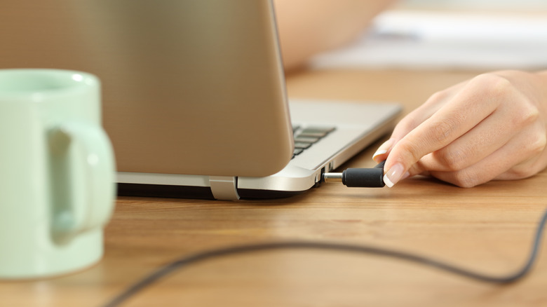 Closeup of a women plugging in the charger to her laptop