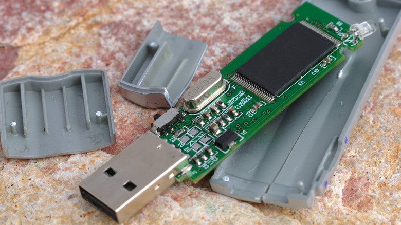 Broken flash drive with internal components visible lying on the floor