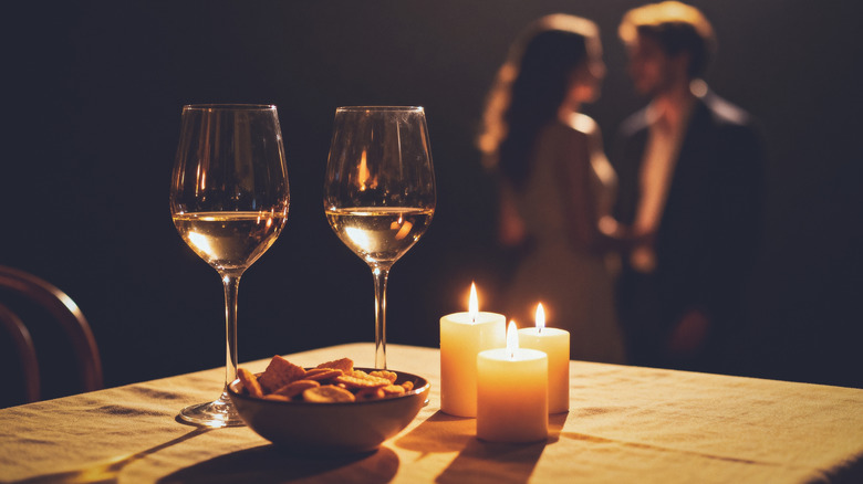 Wine glasses on table with romantic couple in background