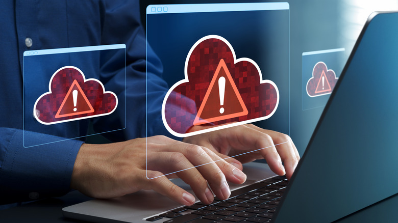 Person using computer with virtual error cloud illustrations on display over their hand