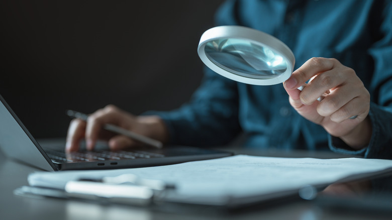 Close-up of a person using a magnifying glass to inspect documents