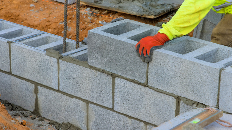 A construction worker placing concrete blocks.