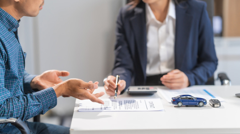 A person asking questions about car insurance at the dealership.