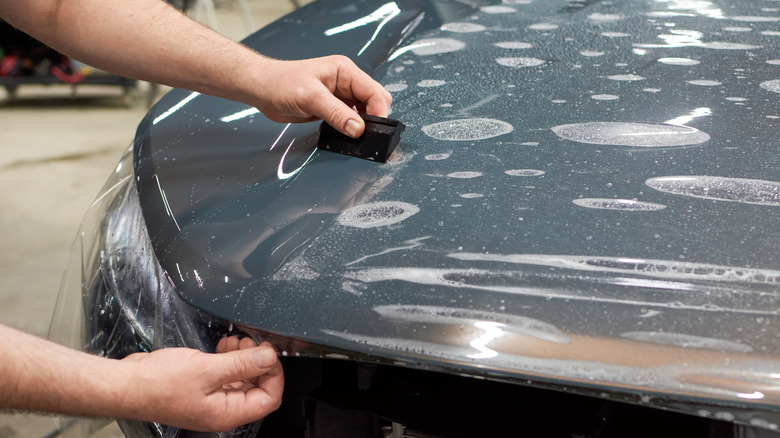 A professional applying paint protection film to a car.
