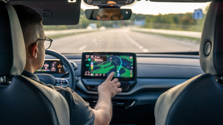 Man touching screen of a GPS navigation system in his car