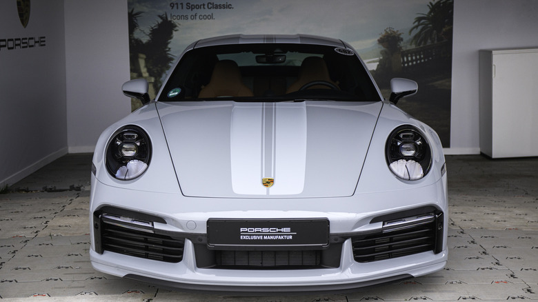 Modern Porsche 911, bright gray with white racing stripes, front-view