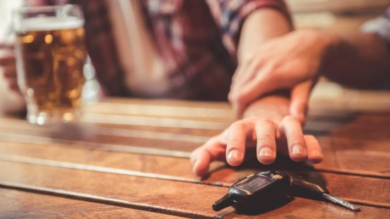 Reaching for car keys with beer in hand