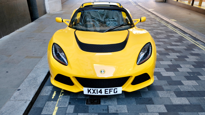 Yellow Lotus parked on a narrow road covered with pavers.