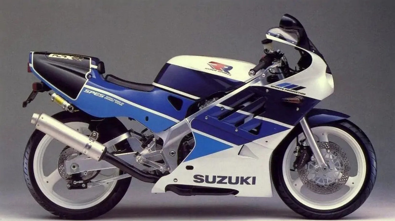 Side view of a 1989 Suzuki GSX-R250R SP in blue and white racing livery, featuring aerodynamic fairings, a single seat, and "SP" and "Sports Production" decals on the tail and fairing.