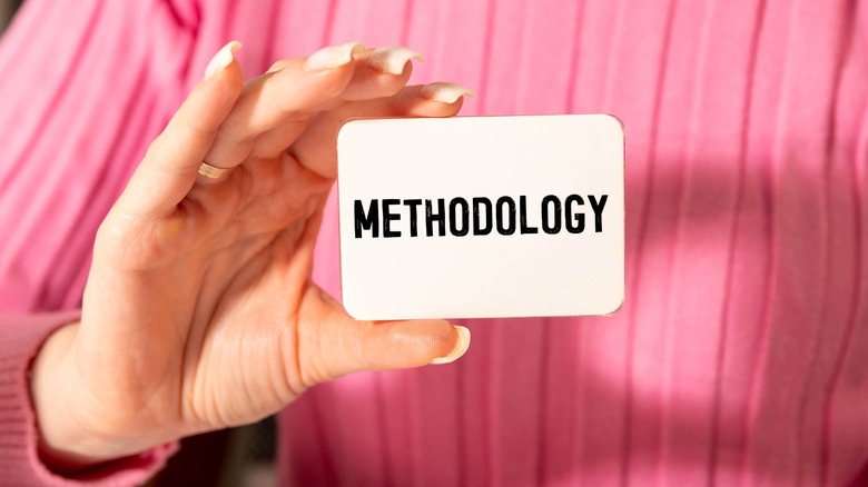 A woman holding up a card that says "Methodology".