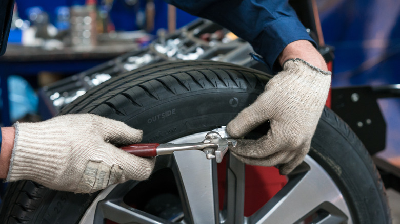 Close-up shot of tire technician installing a weight on tire for balancing purposes