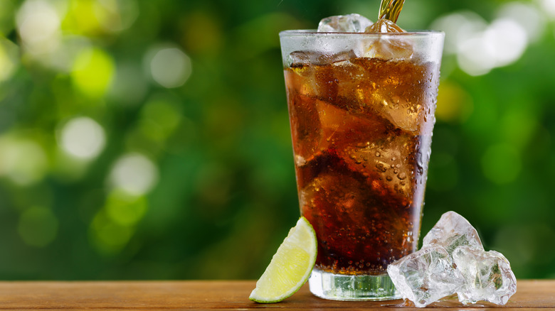 Ice cold glass of soda with cubes and lime wedge