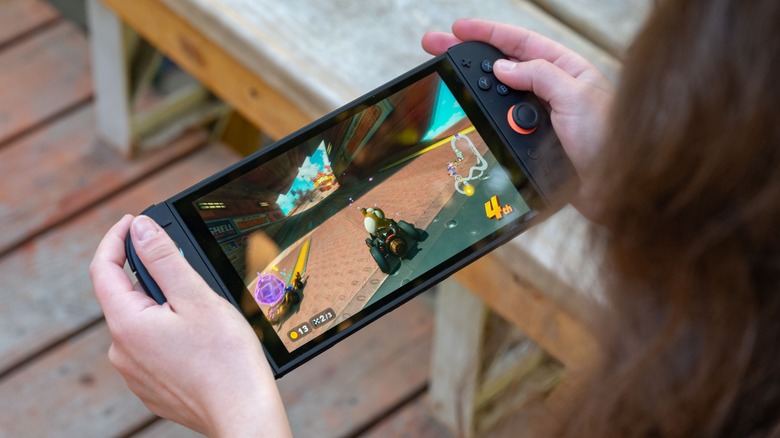 The Nintendo Switch 2 with Mario Kart 2 playing on screen, held in a persons hands.