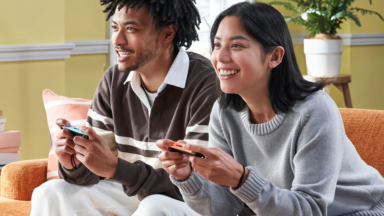 Two people playing the Nintendo Switch 2 with Joy-Cons on a sofa.