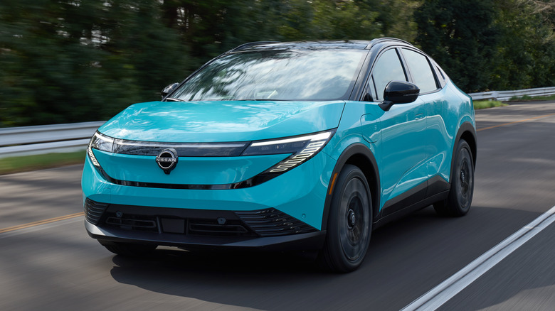 A light blue new Nissan Leaf electric crossover driving on a highway.