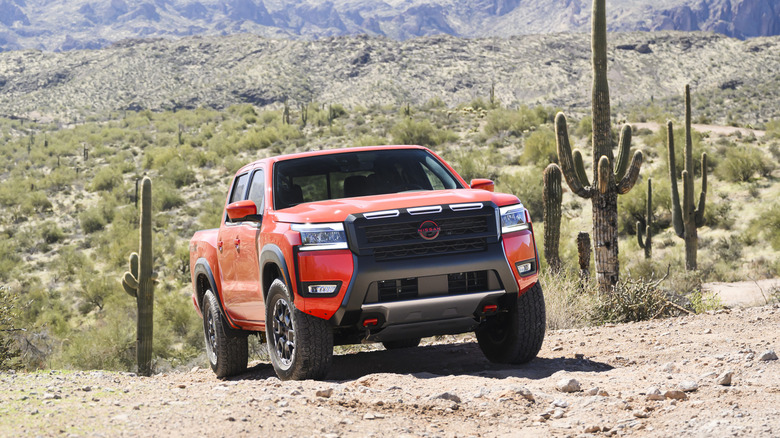 Frontal view of a aed 2026 Nissan Frontier driving in the desert.