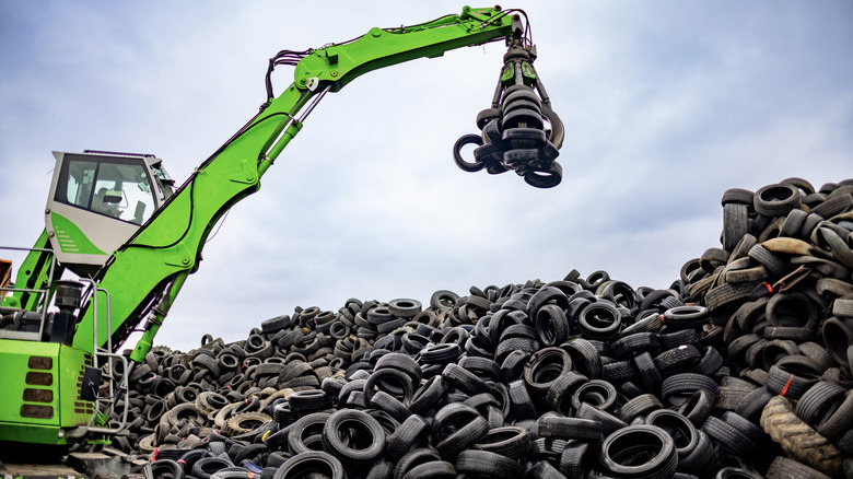 A material handler machine lifting a stack of tires in a tire dump
