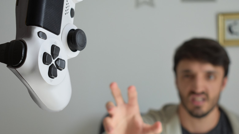 angry man throwing playstation controller