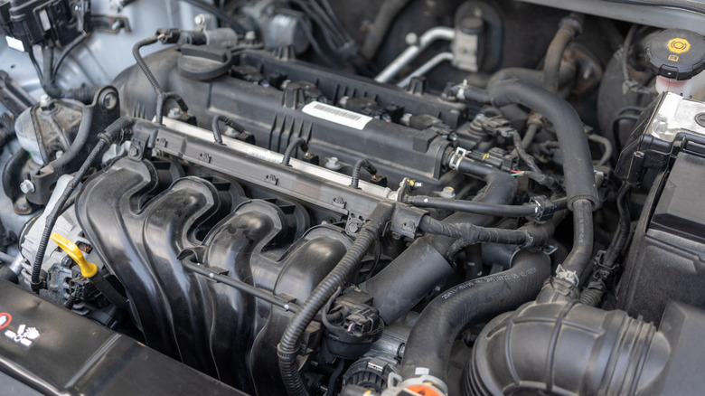 An unidentified four-cylinder engine under the hood of a car