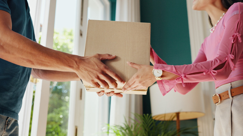 door delivery concept; man handing a woman a sealed box