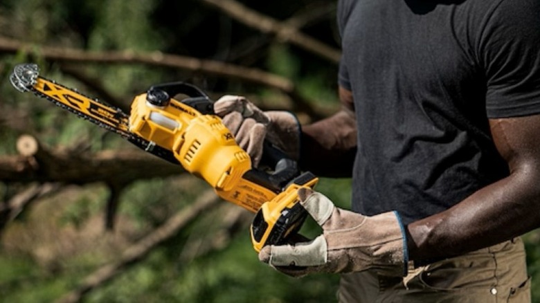 A man replacing the battery on a DeWalt pruning chainsaw.