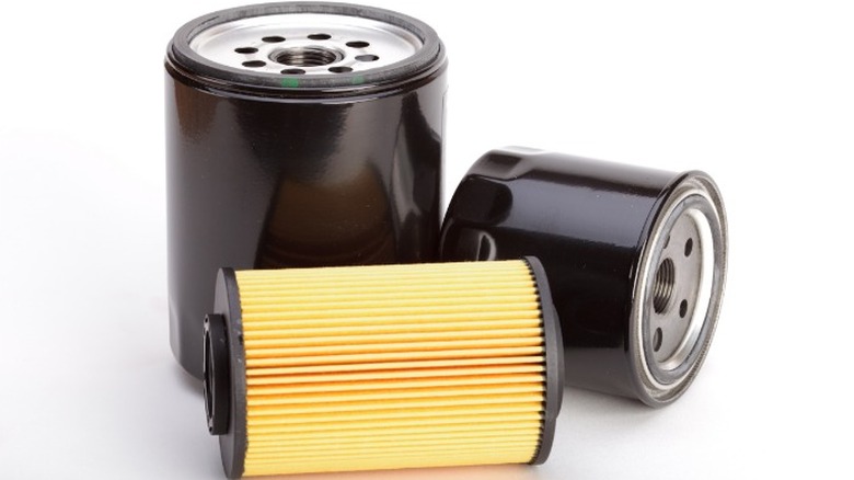 An image of three different car oil filters, including one canister filter and two spin on metal filterse