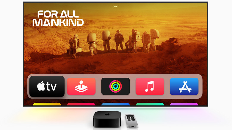 A flat screen Apple TV and remote all laid out on a blank background with smart TV apps on display