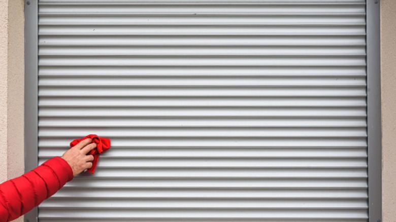 Hand with rag cleaning garage door shutters