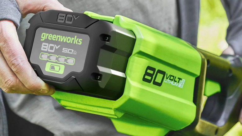 A person installing a Greenworks battery