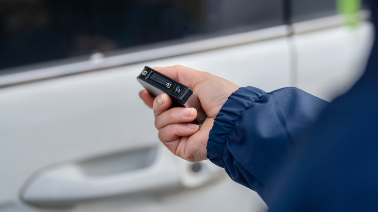 A woman using the remote key to open the car door.