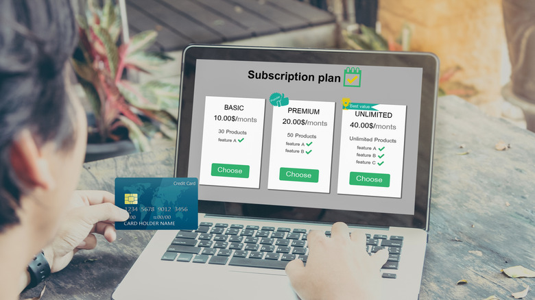 holding a credit card in front of a subscription screen