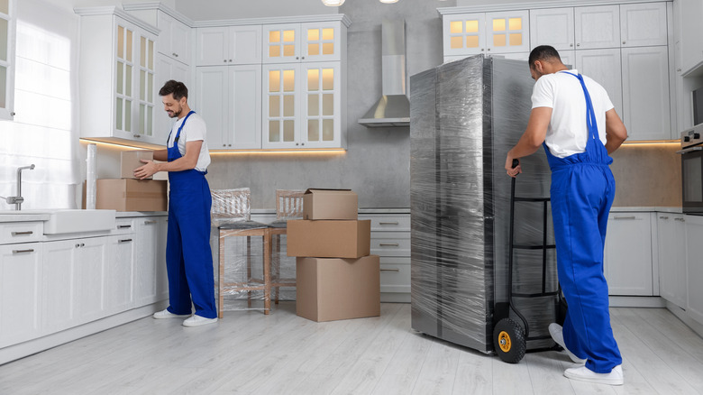 Two men installing new kitchen appliances including fridge